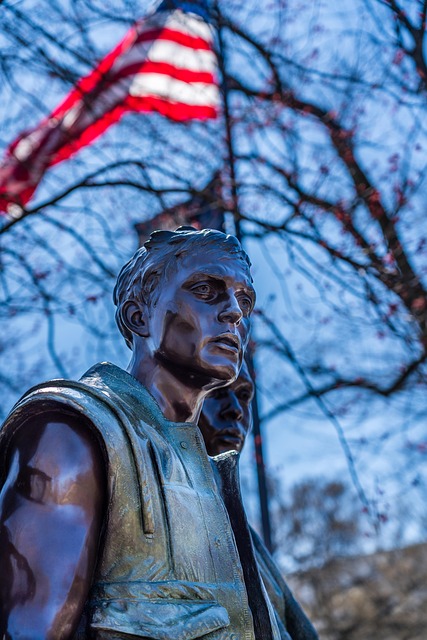 Veterans memorial statue beneath American flag, honoring service and dignity through cremation services Royal Oak, MI