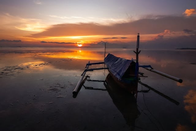 Peaceful boat at sunrise on calm waters, reflecting serenity and remembrance near cremation services Berkley, MI.