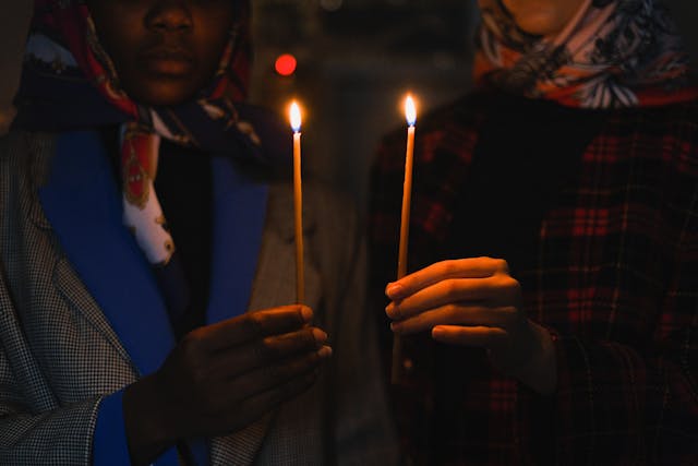 Two people holding thin candles during cremation services Sterling Heights, MI, offering a peaceful, solemn tribute.